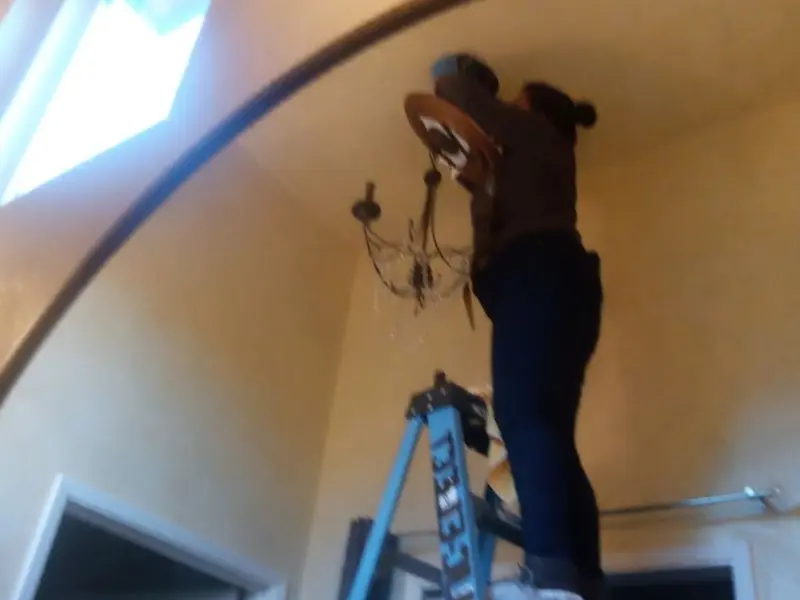 Electrician installing a chandelier in a Yulee residence